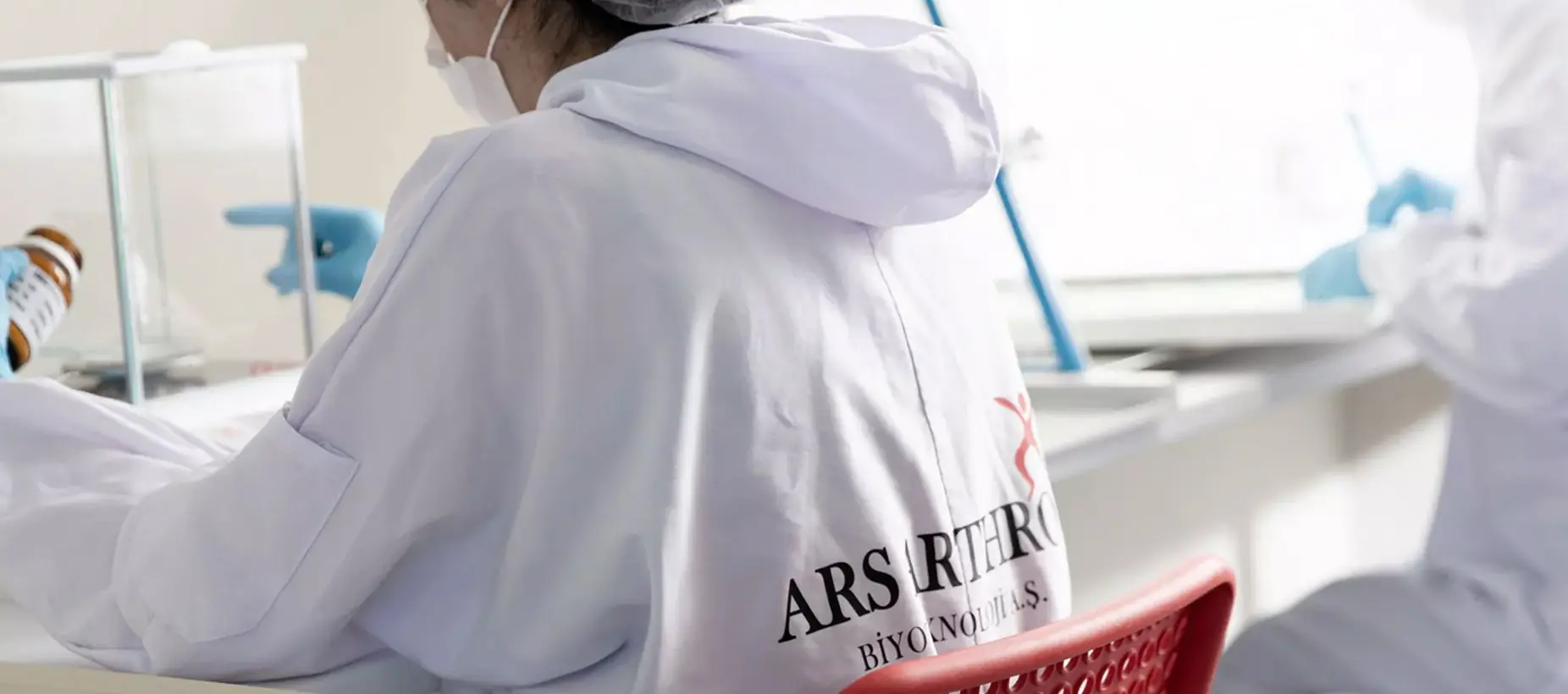 Researcher wearing a lab coat with the Ars Arthro logo on the back