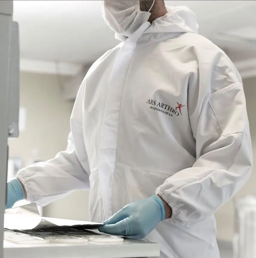 Ars Arthro logolu önlüğüyle laboratuvarda çalışan araştırmacı