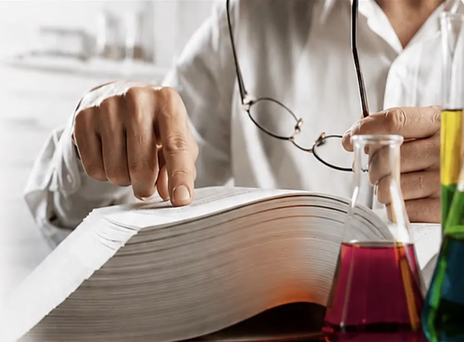Kalın bir bilimsel kitabı inceleyen araştırmacı